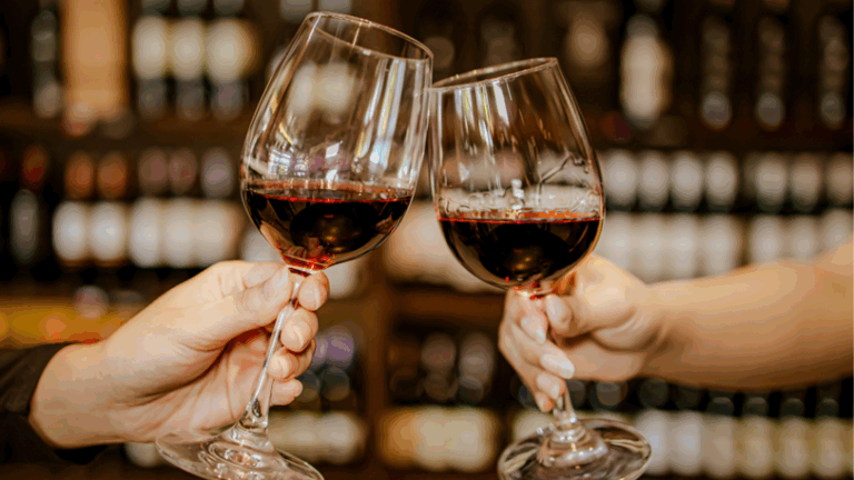 Two wine glasses with wine being clinked together in a cheers